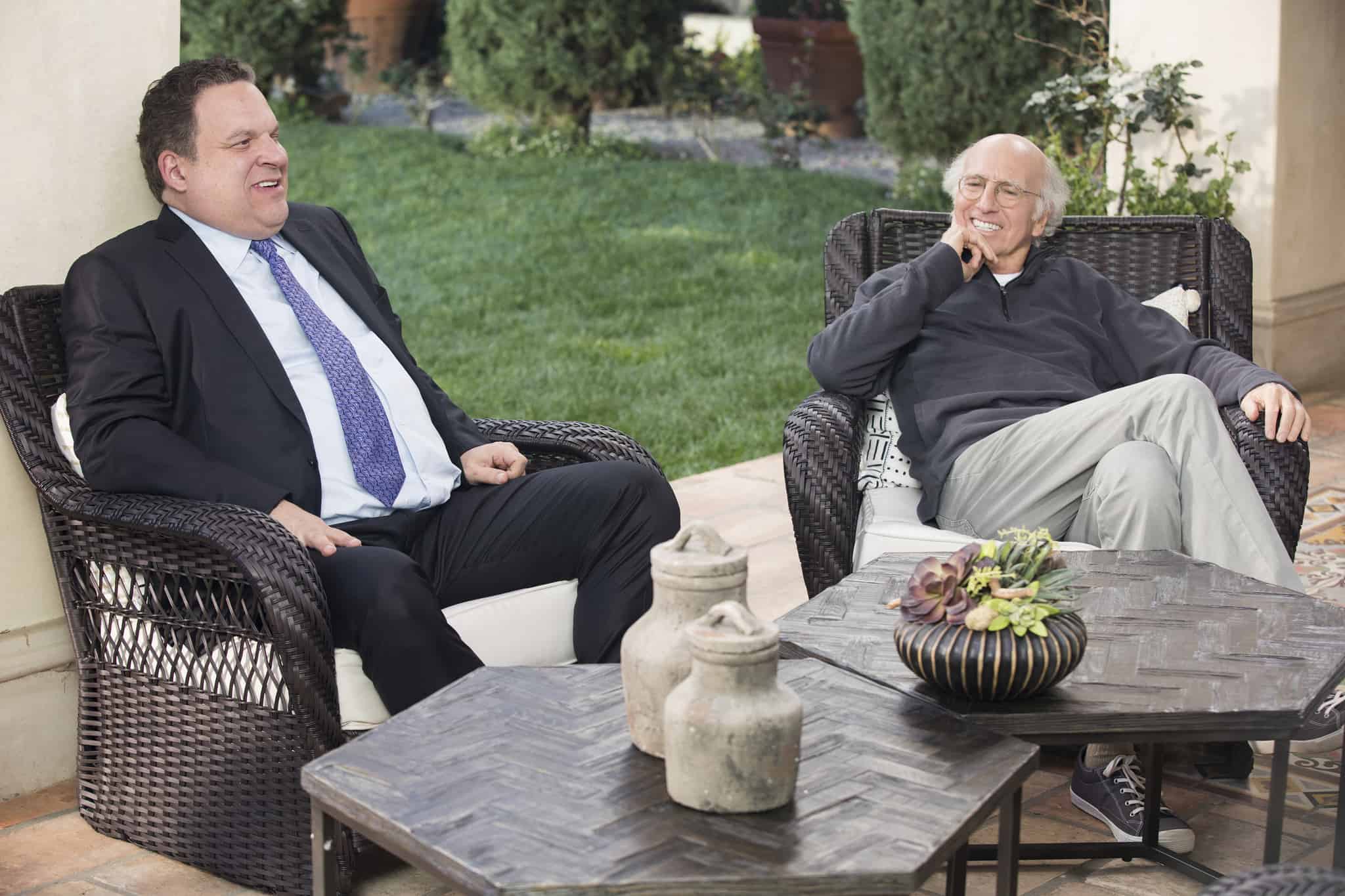 Two men sit on a garden patio in this image from HBO.
