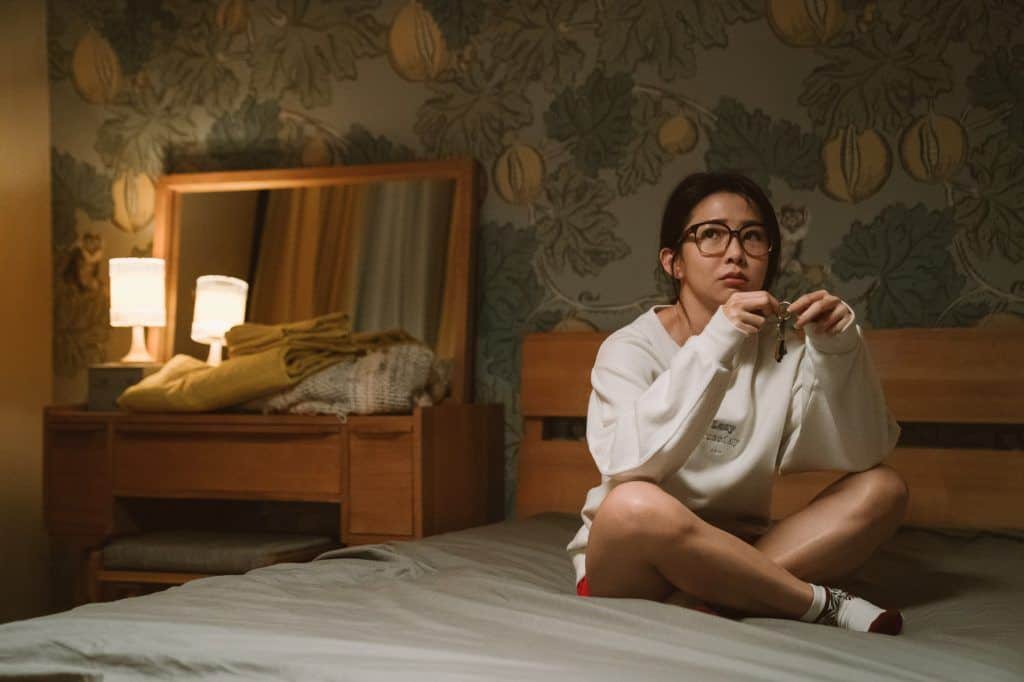 A woman sits on a bed playing with keys in this image from HBO Asia.