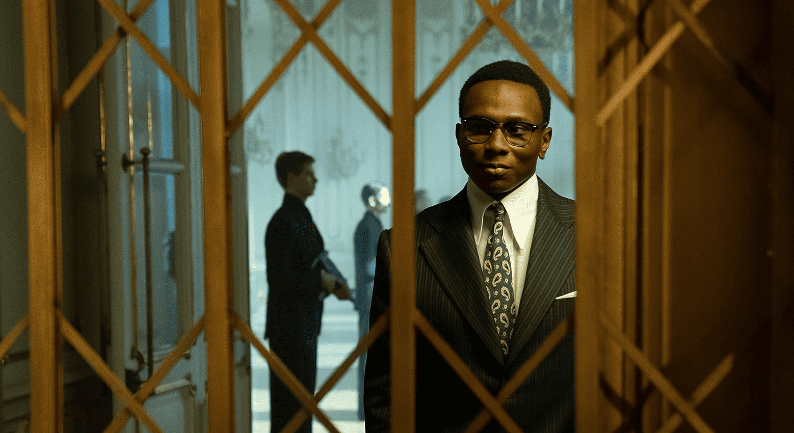 Ayomide Adegun portrays a young Charon standing behind the hotel’s recognizable golden doors in this image from Thunder Road Pictures.