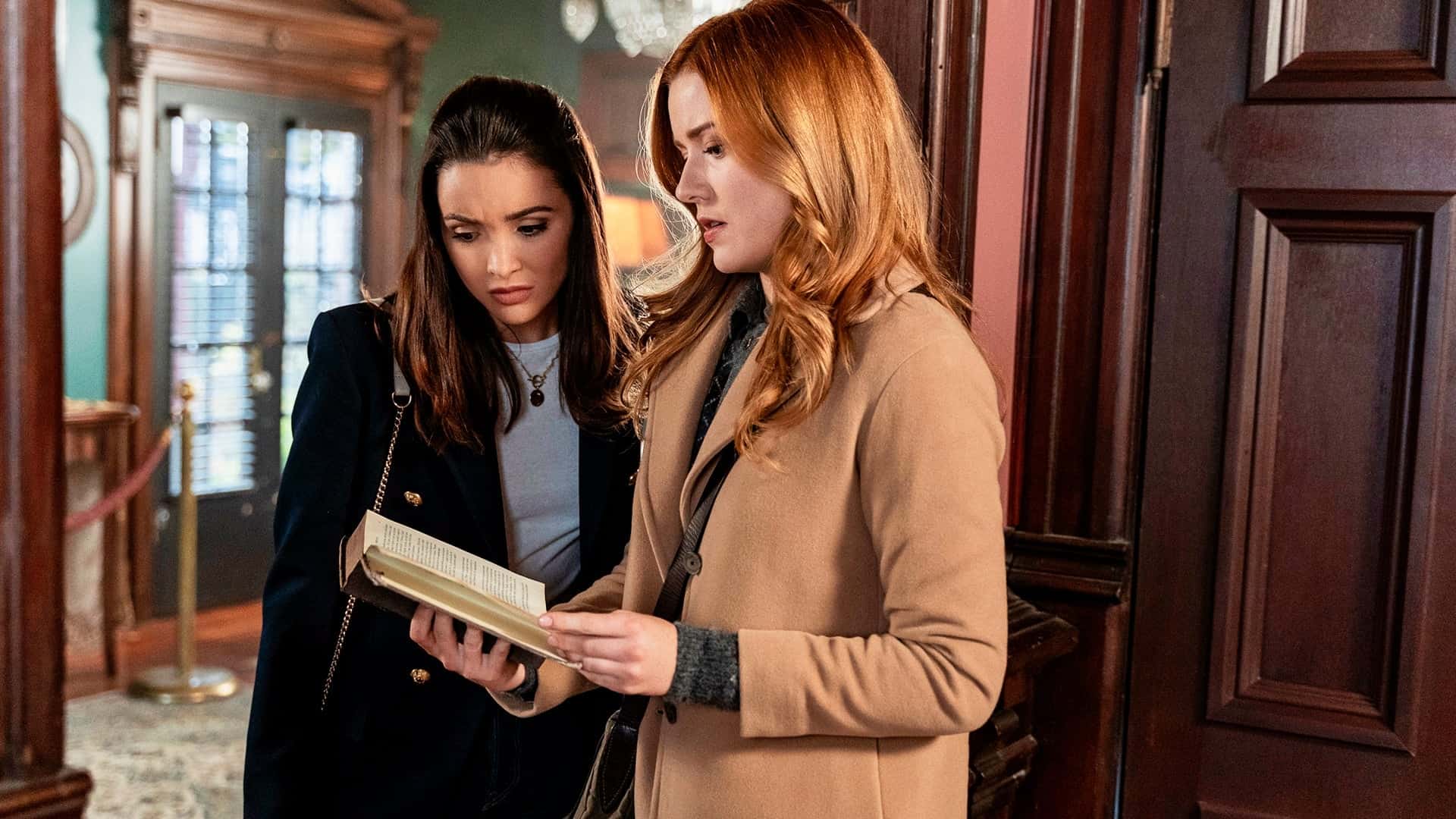 Two girls stand in a doorway and read from a book together in this image from CBS Television Studios