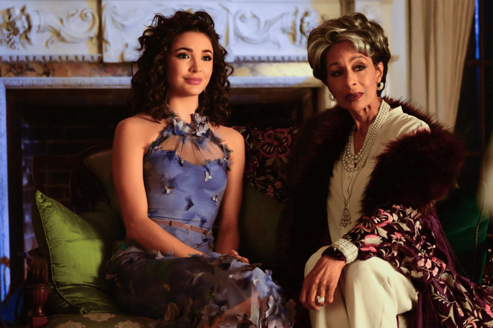 Two women, one younger and one older, sit together at a gathering in this image from CBS Television Studios.