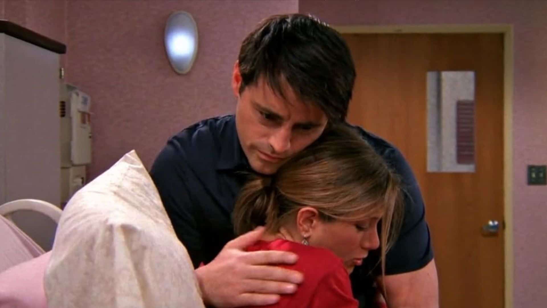 A man and a woman hug in a hospital room in this image from Warner Bros. Television.