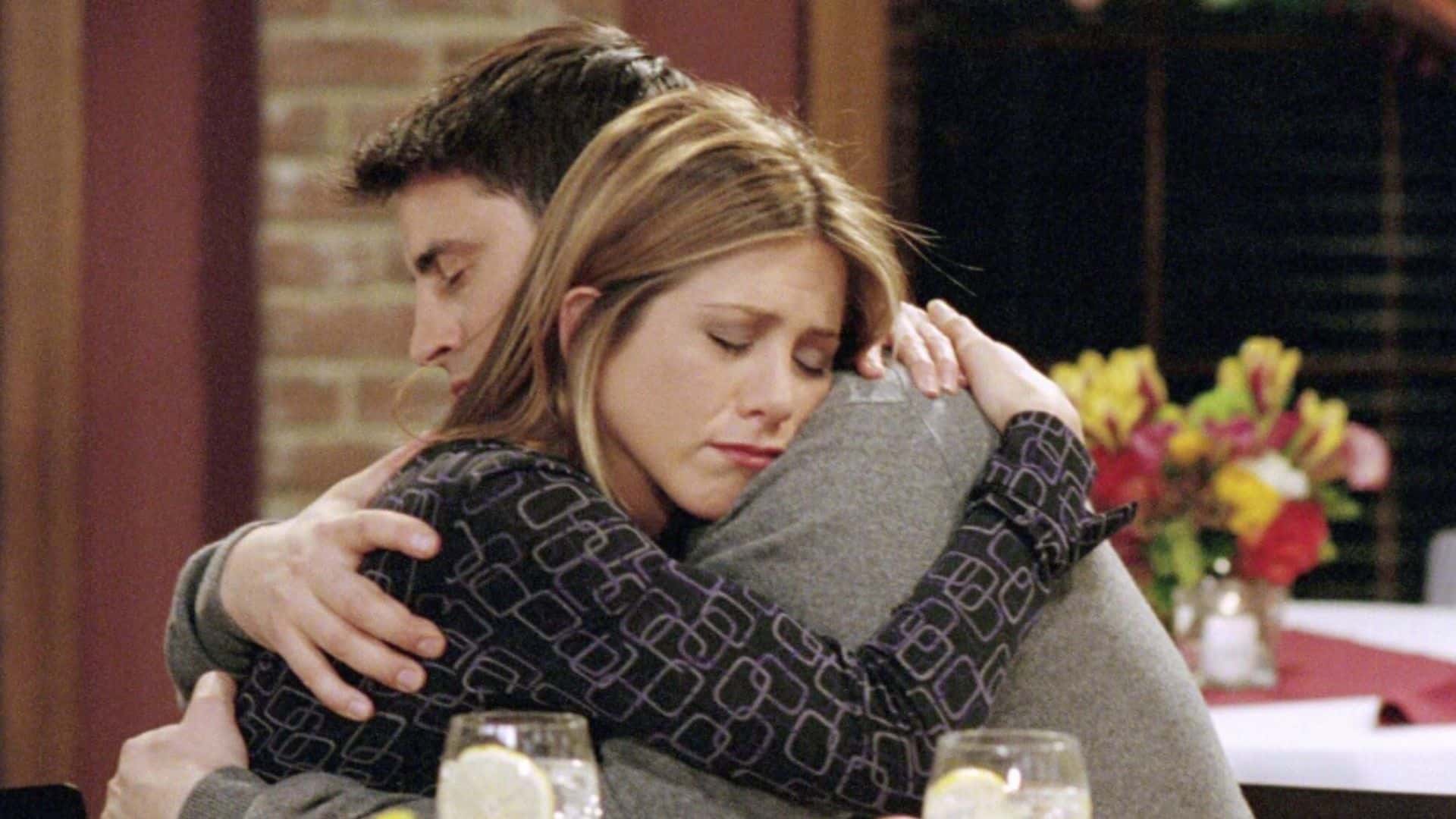 A man and a woman hug in a restaurant in this image from Warner Bros. Television.