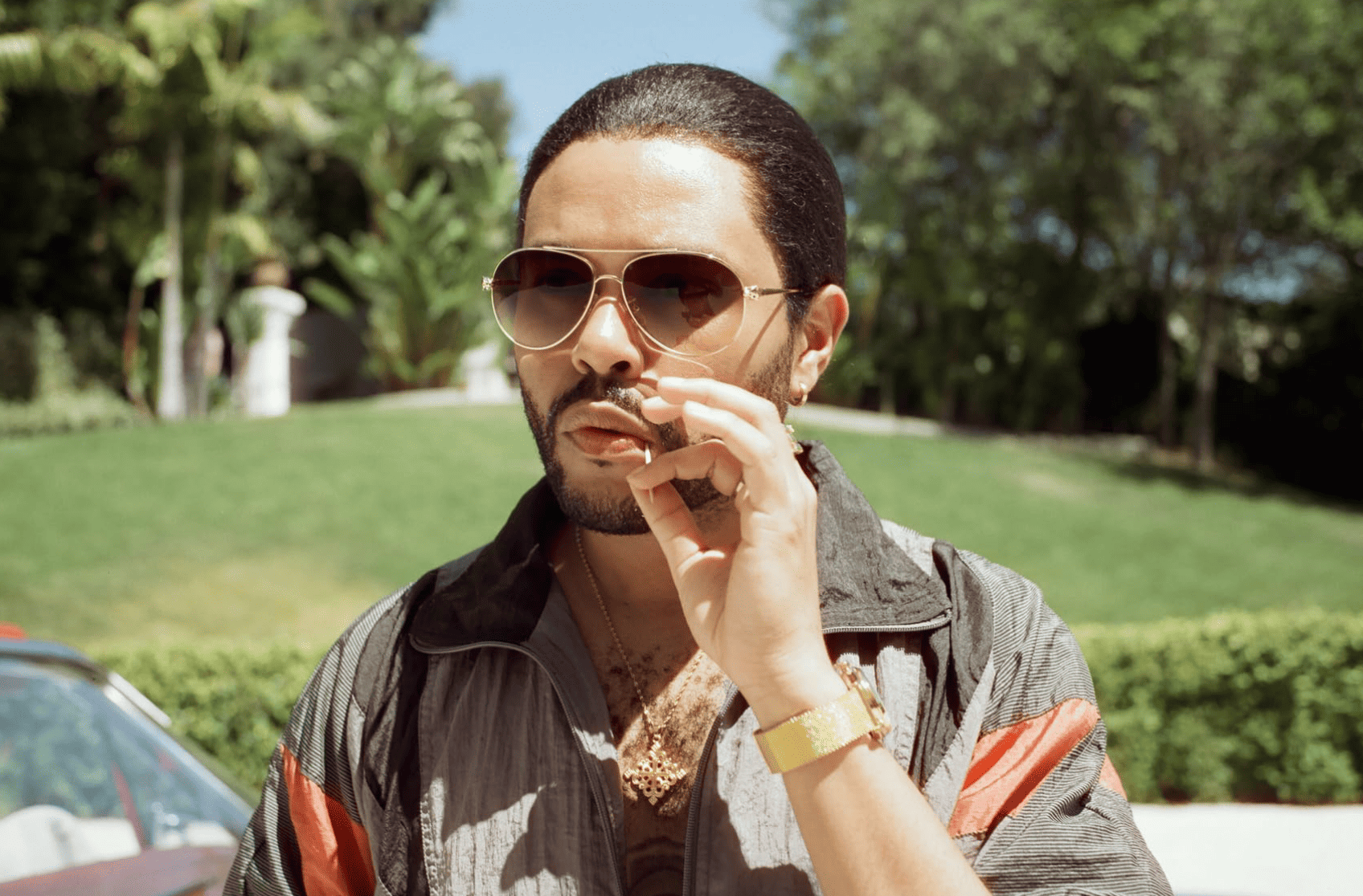 The Weeknd wearing his signature parachute jacket and sleek ponytail while resting a toothpick in his mouth in this image from HBO Entertainment