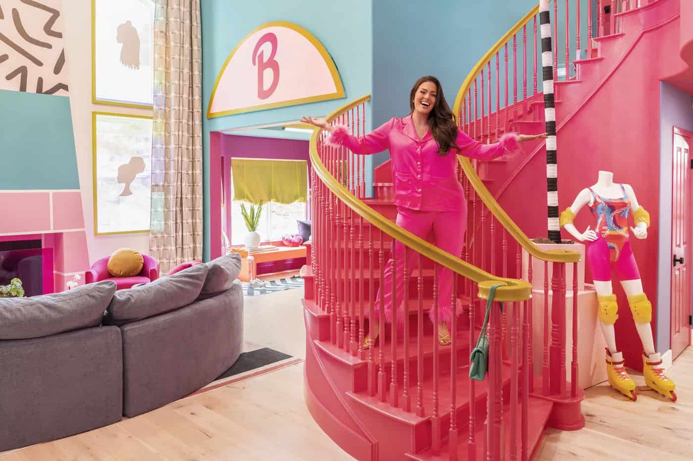 A woman in pink stands inside a life-size Barbie Dreamhouse in this image from Mattel Television.