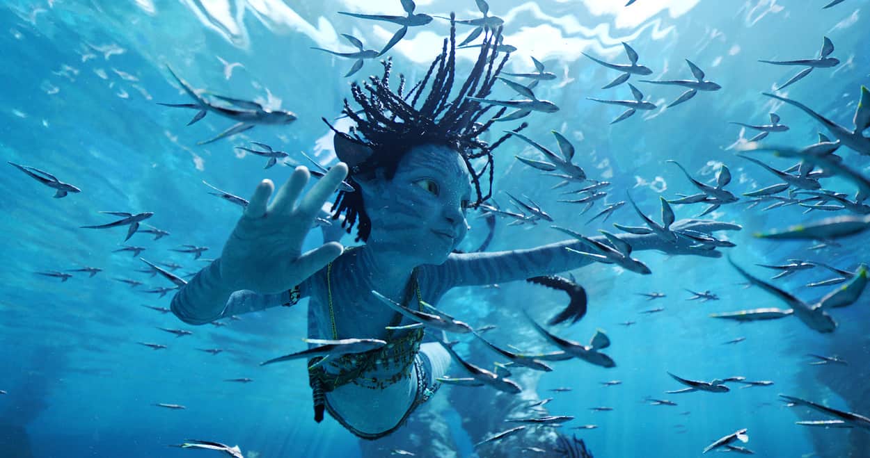 A blue, alien-looking child swims in the water with fish in this image from Lightstorm Entertainment.