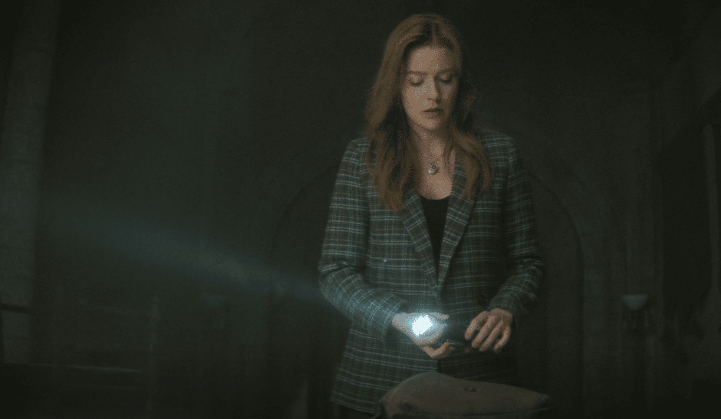 Nancy (Kennedy McMann) with a flashlight as she packs up Nancy Drew Investigations in this image from CBS Television Studios