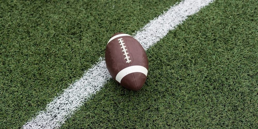A closeup of a football on a football field in this image from Shutterstock.