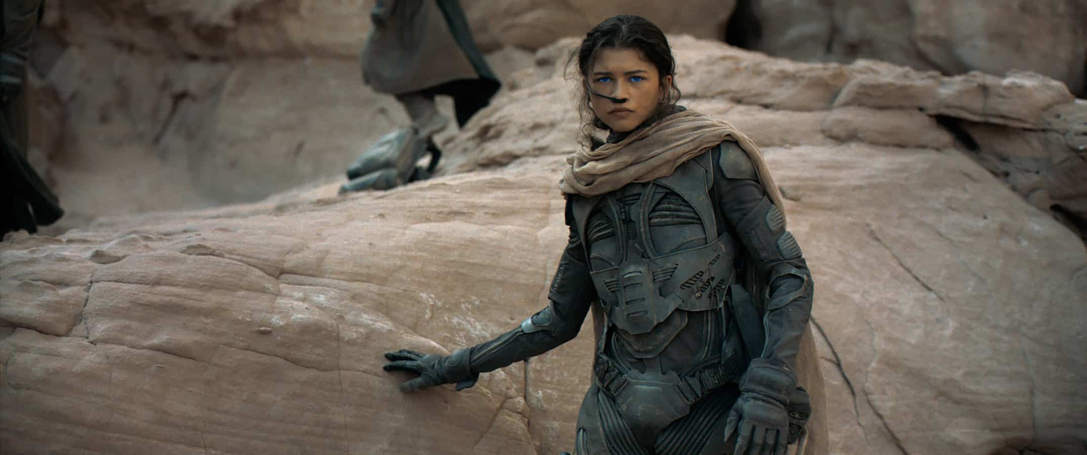 A girl leaning on a rock in sci-fi armor in this image from Legendary Pictures.