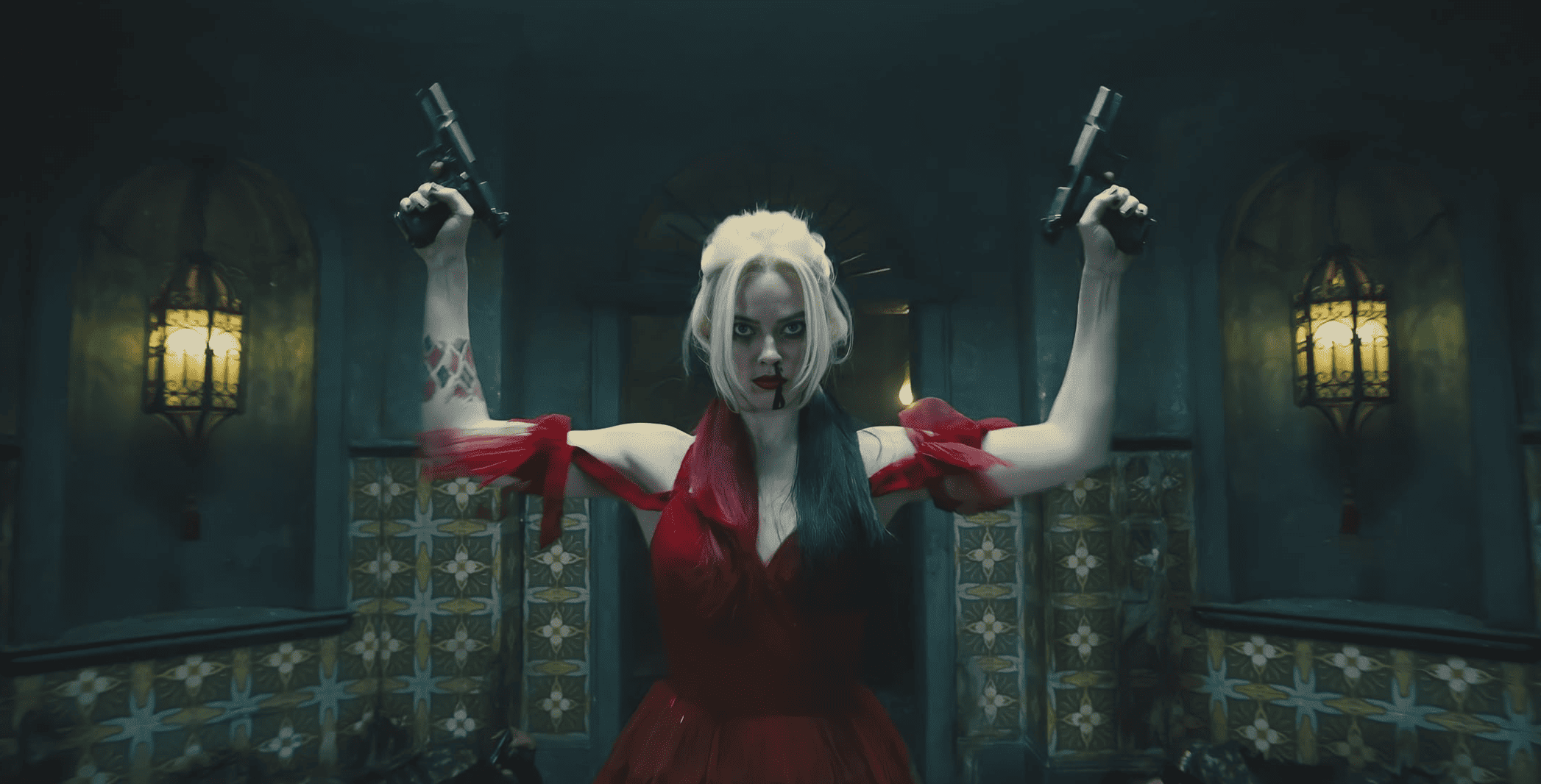 Harley in a red dress and a gun in each hand in this image from DC Entertainment