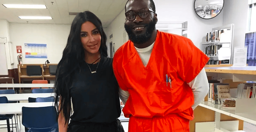 A woman dressed in black stands next to a male dressed in an orange prison jumpsuit in this photo from Instagram.