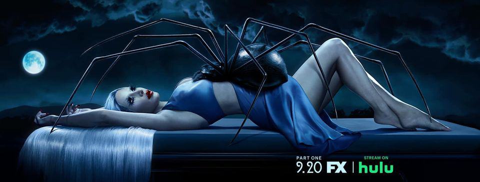 A woman lays on a table under a moon and dark sky, with a large spider on her midsection in this photo by Ryan Murphy Television. 