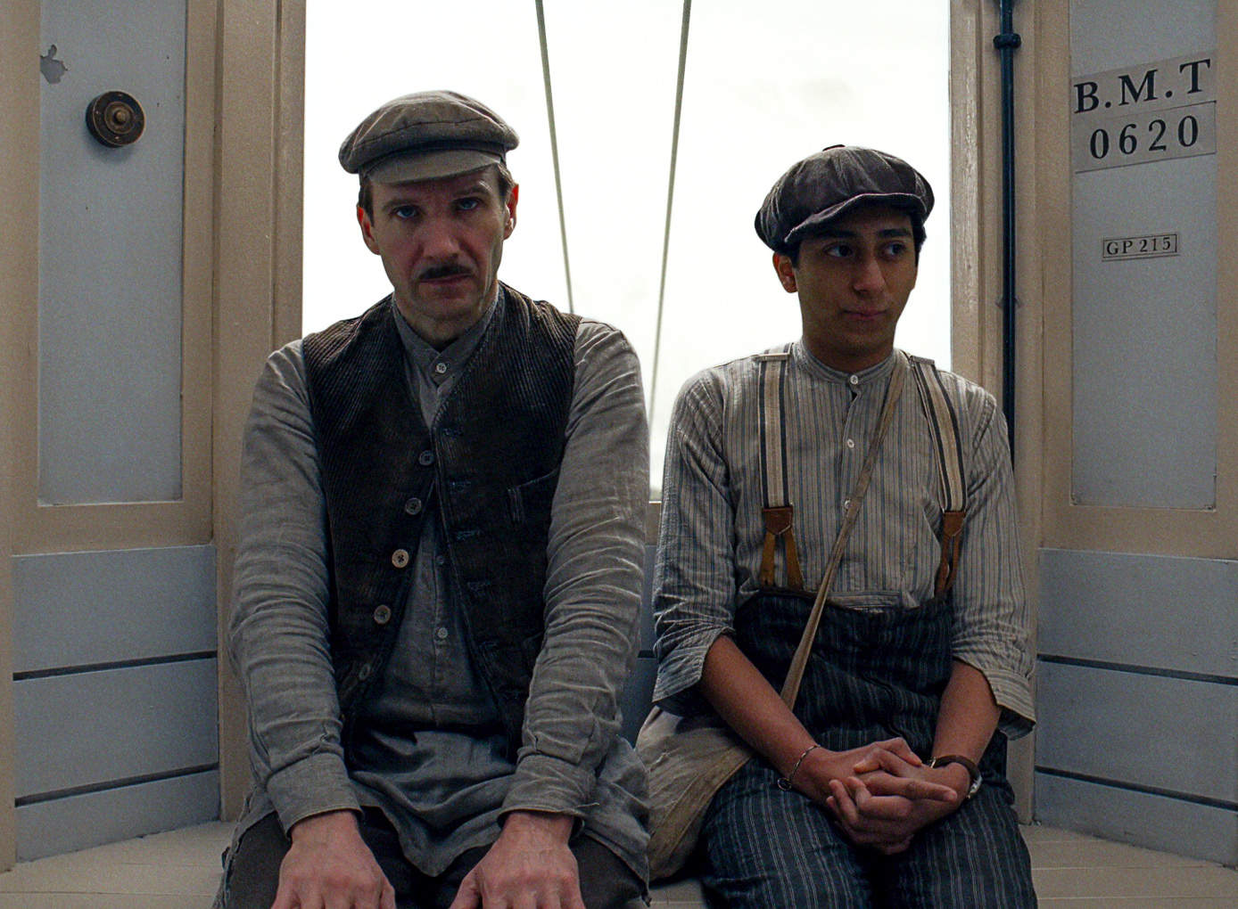 A man and a boy sit together in worker’s clothes in this image from Fox Searchlight Pictures.