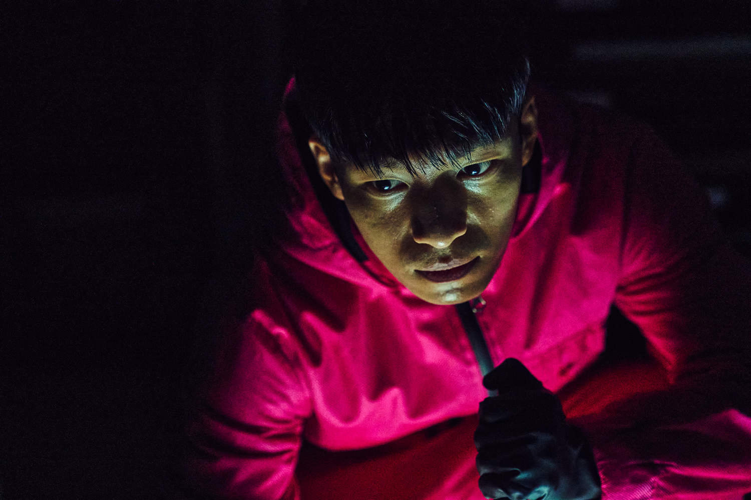 A man in a pink suit crawls with a flashlight in this image from Siren Pictures Inc.