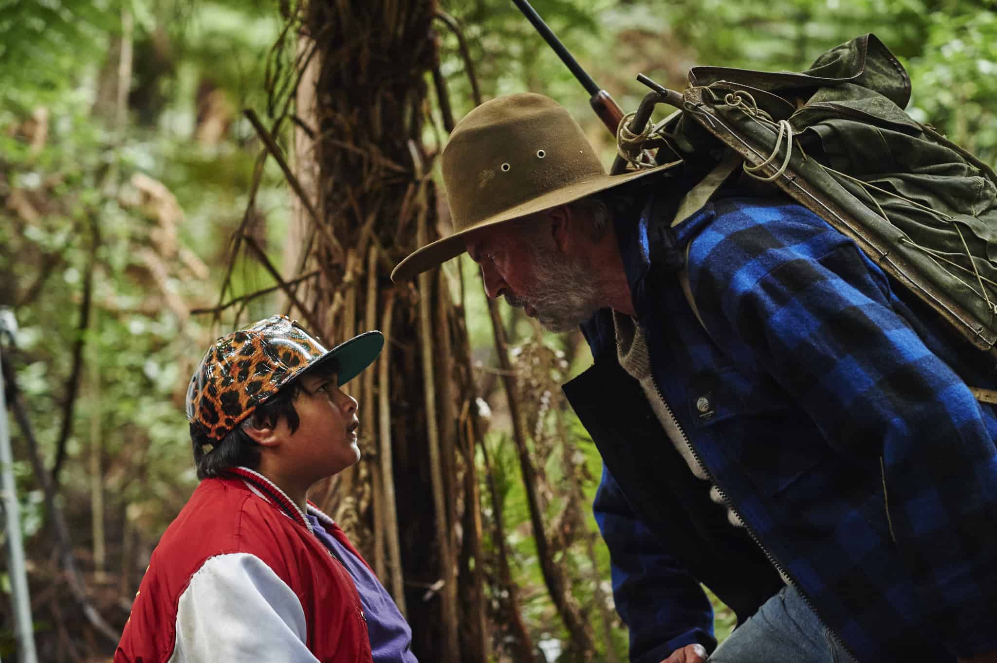 A young boy and a man talk in the woods in this image from Piki Films