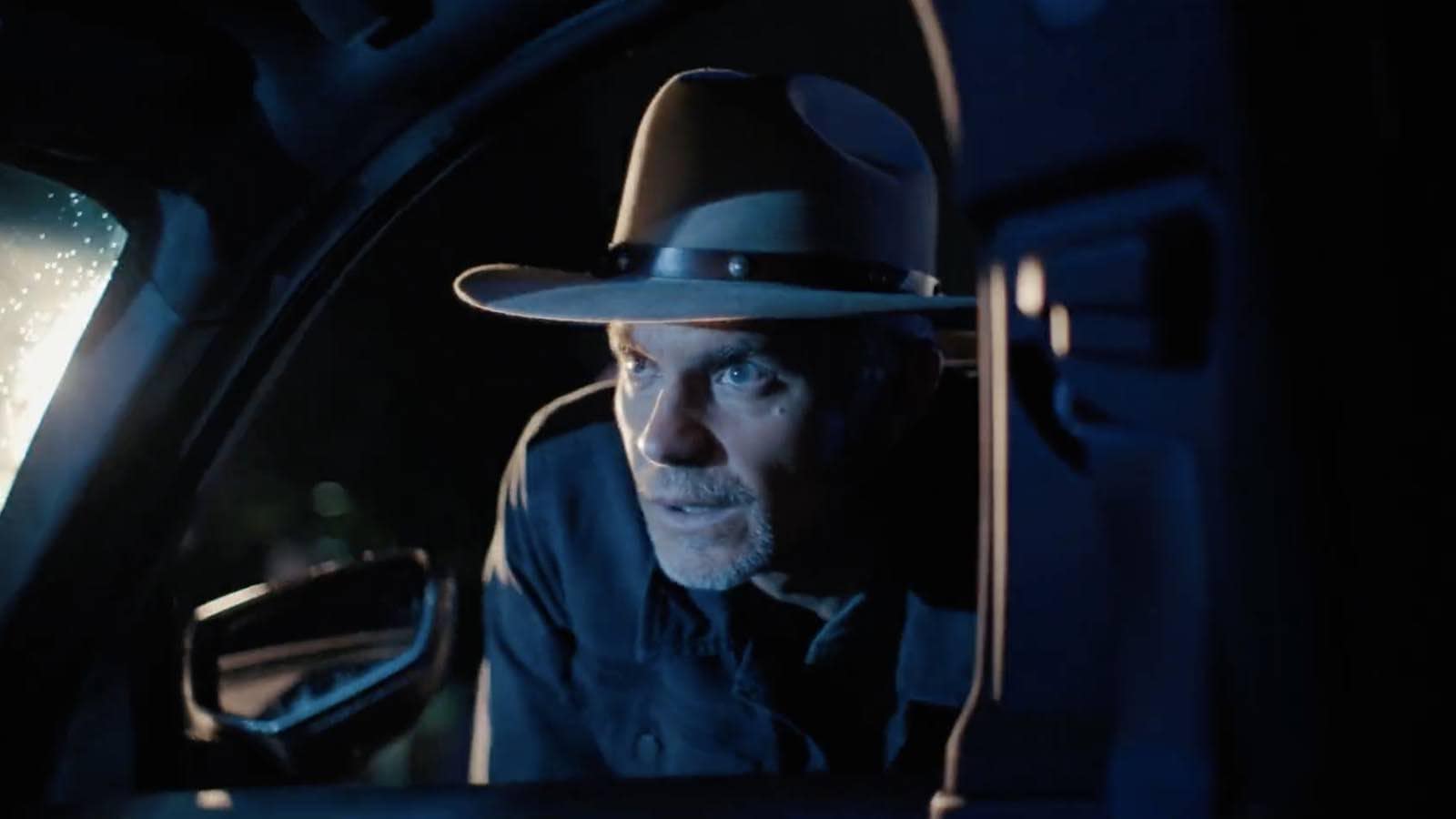 A man in a cowboy hat leans into a car window in this image from FX Productions.