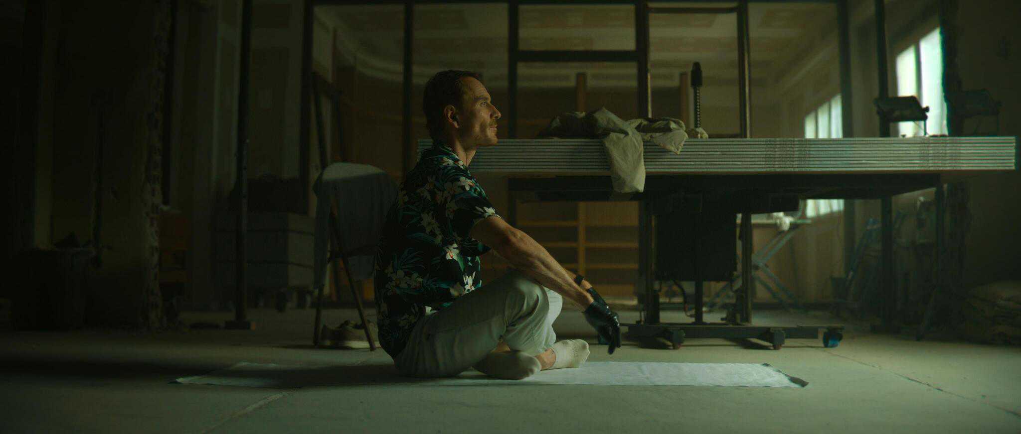 A man in leather gloves sits cross-legged on the floor in this image from Netflix Studios.