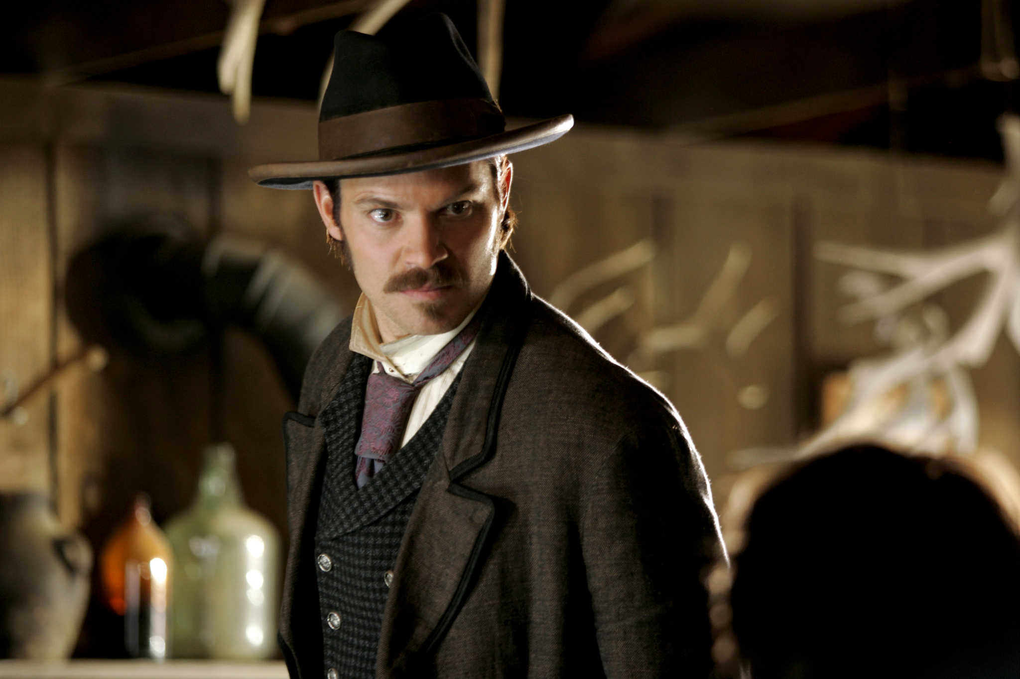 A mustached man glares at someone in a saloon in this image from Roscoe Productions.