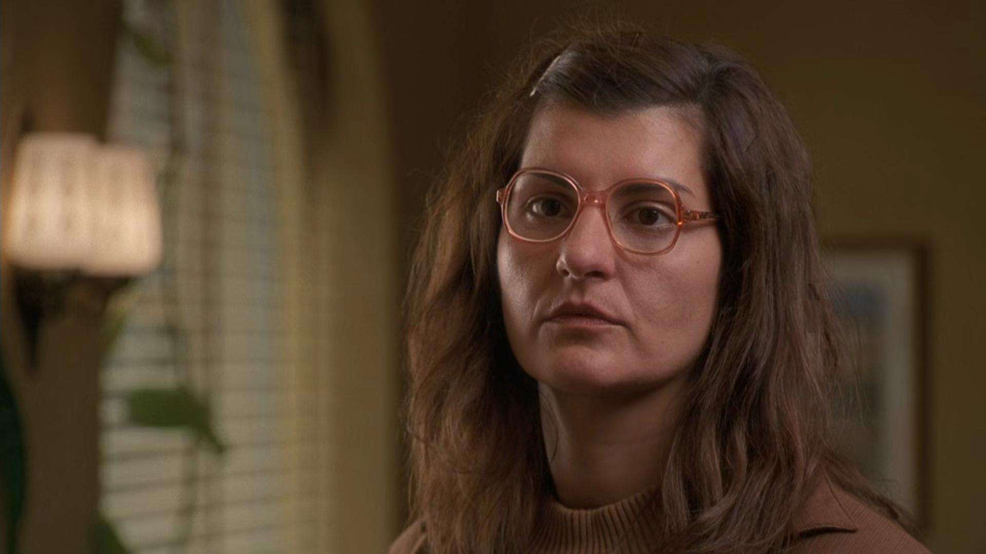 A woman in glasses stares at something off-screen in this image from Gold Circle Films.