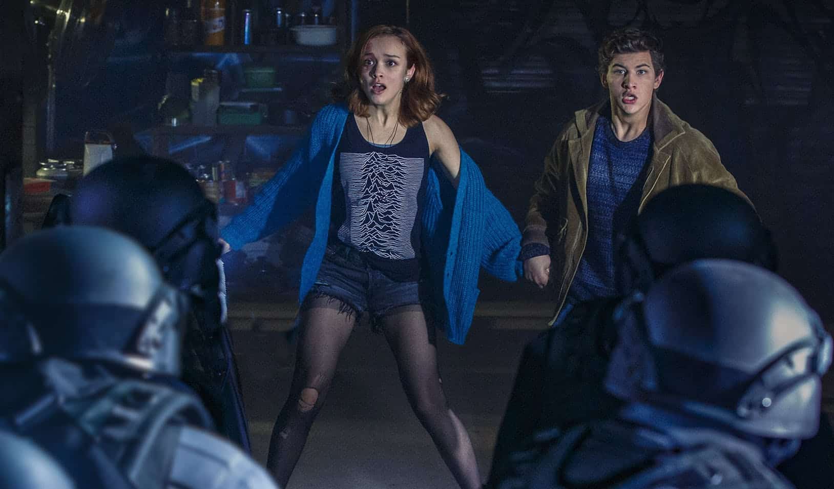 A teen girl and boy face off with soldiers in this image from Warner Bros. Pictures.