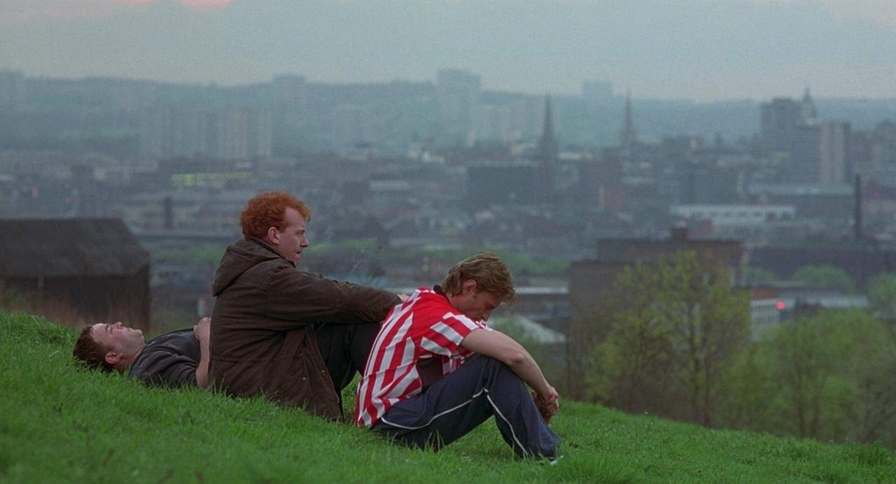 Three young men sit and lay down on the hills in this image from Redwave Films.