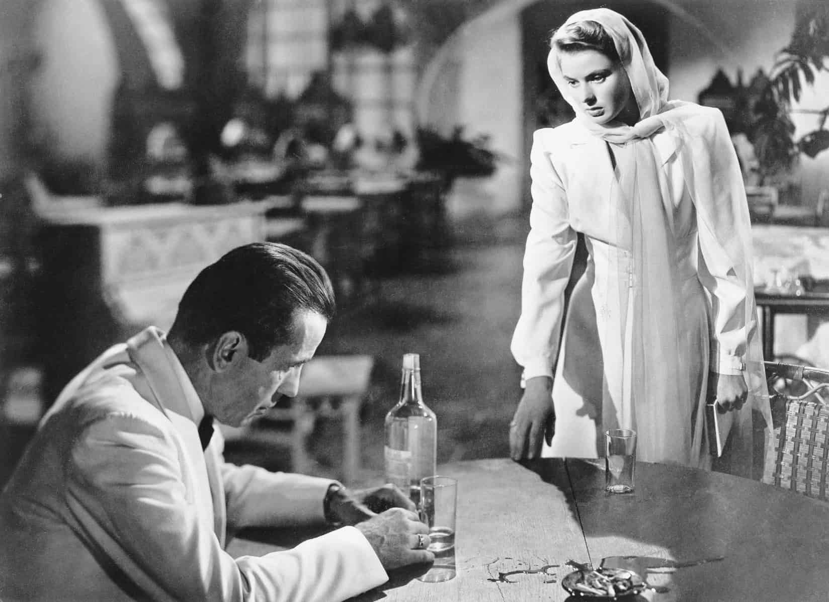 A woman standing at a table across from a seated man in this image from Warner Bros.