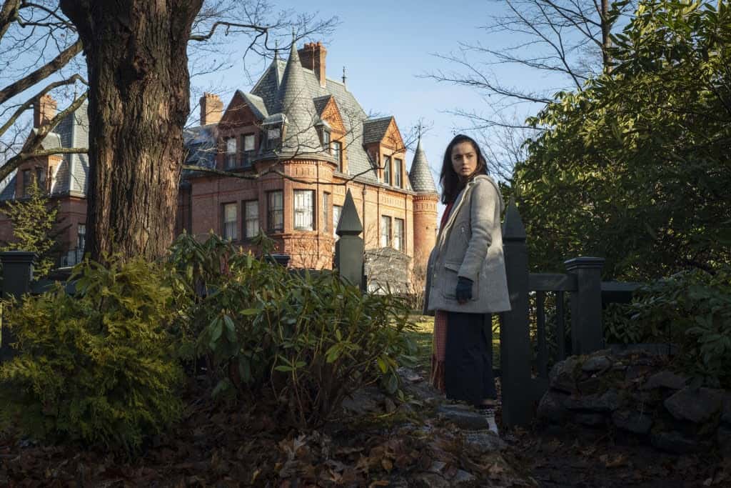 A girl looks over her shoulder from the gate of a Victorian mansion in this image from Lions Gate Films.