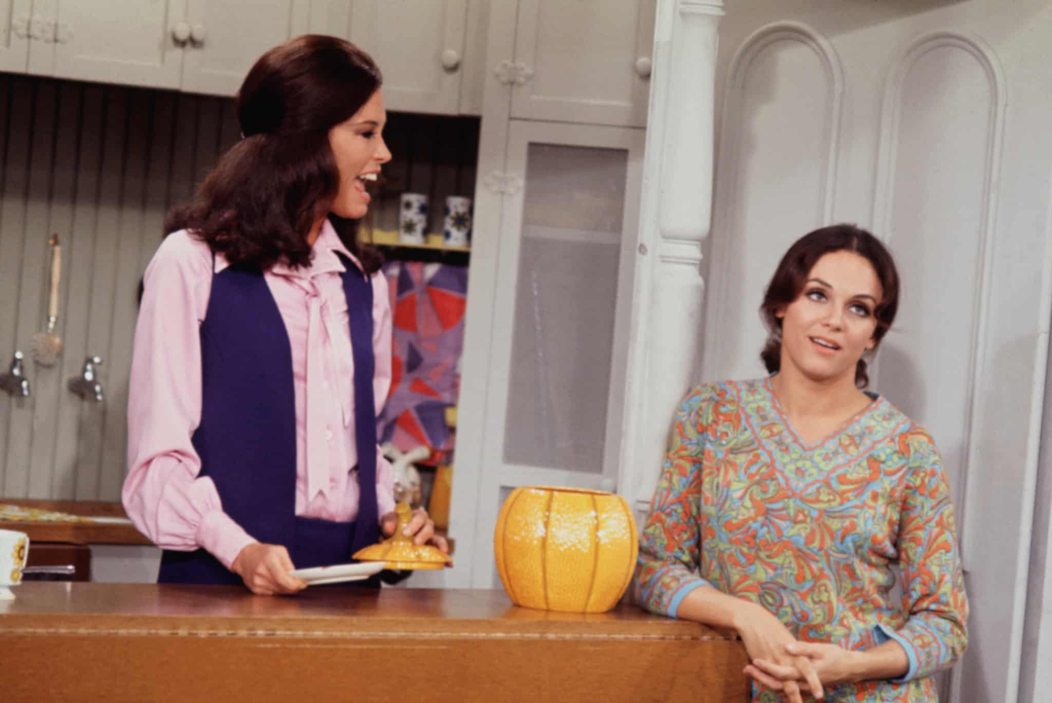 Two women hang out in a kitchen in this image from MTM Enterprises.