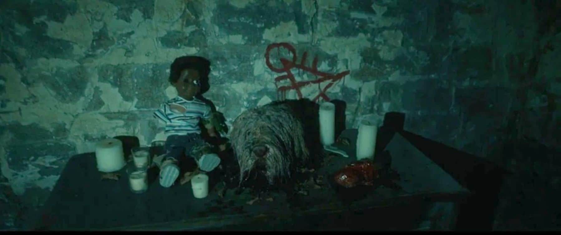 A doll, a dog’s head, and some candles adorn a table in this photo by Showtime.