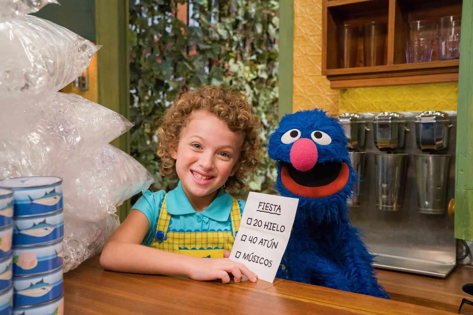 A young girl learning Spanish with Grover in this image from Sesame Workshop
