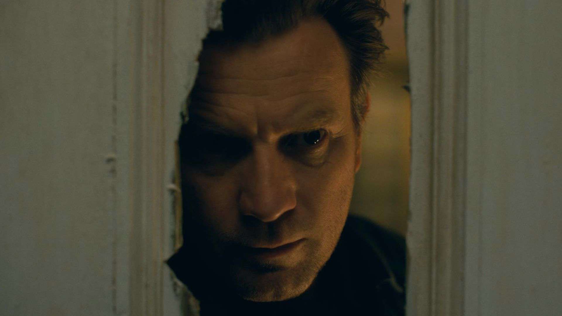 A man looks through a hole in a destroyed door in this image from Warner Bros. Pictures