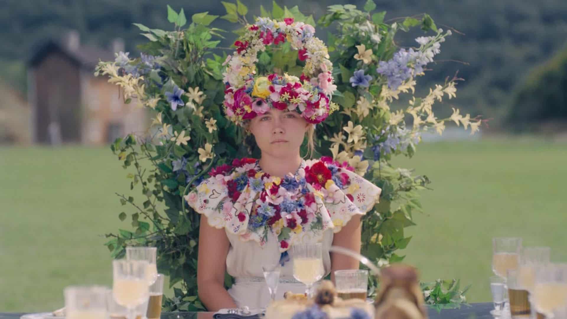 A woman sits at the head of a table adorned with flowers in this image from A24.