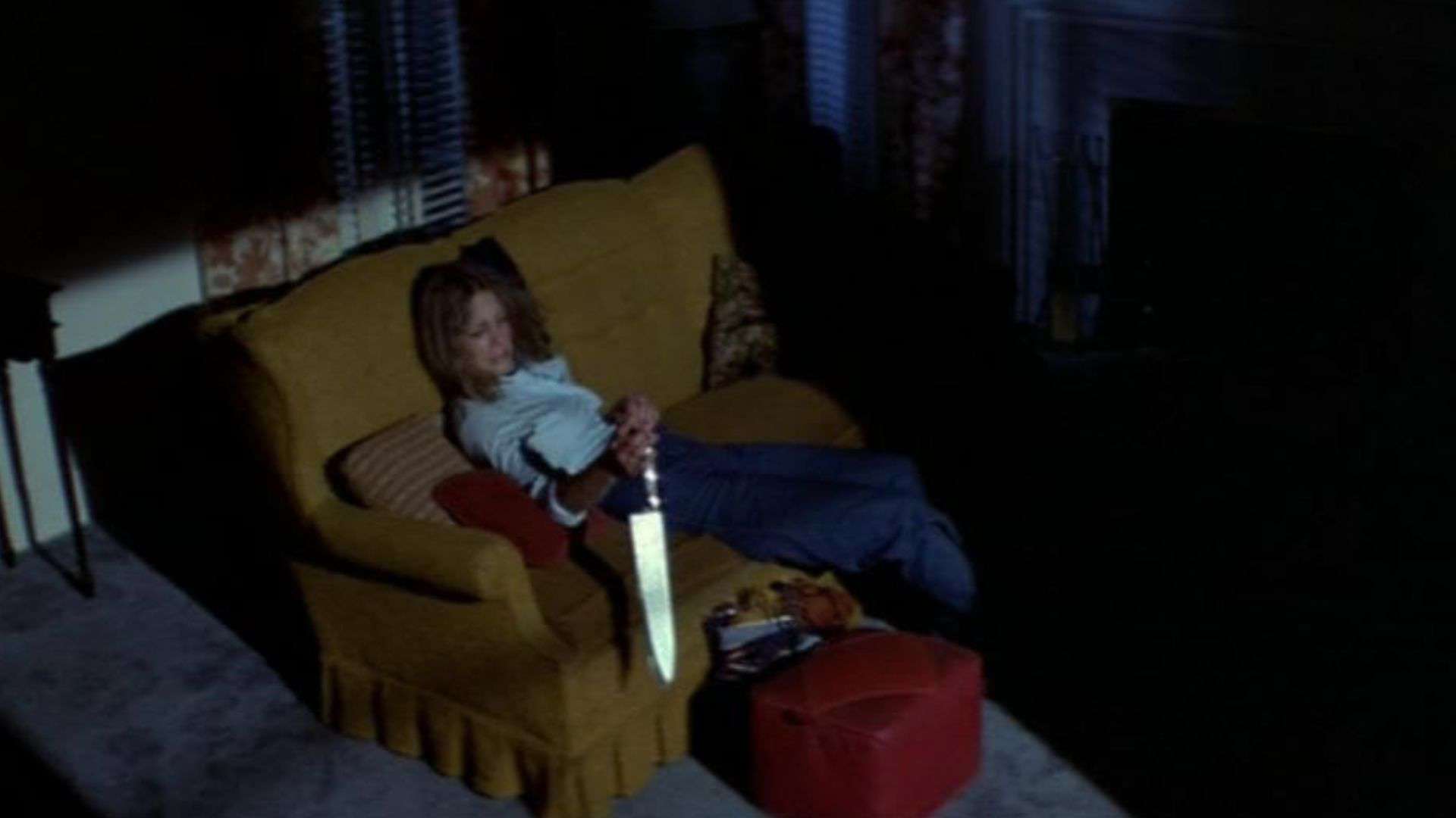 A woman sits on a couch holding a knife in this image from Compass International Pictures.
