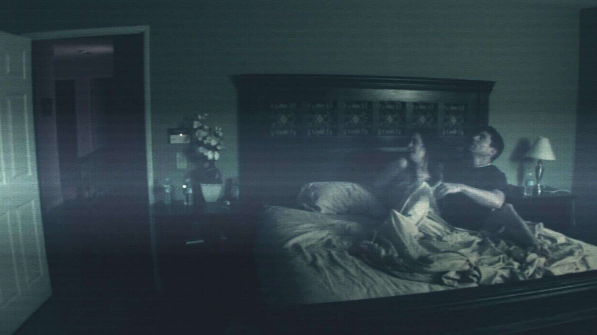 A couple sits up scared of something in bed in this image from Blumhouse Productions.