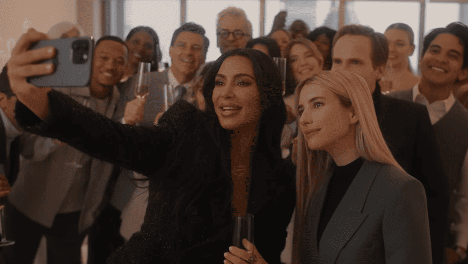 A woman takes a selfie with a group of people holding Champagne glasses in this image from Ryan Murphy Television.