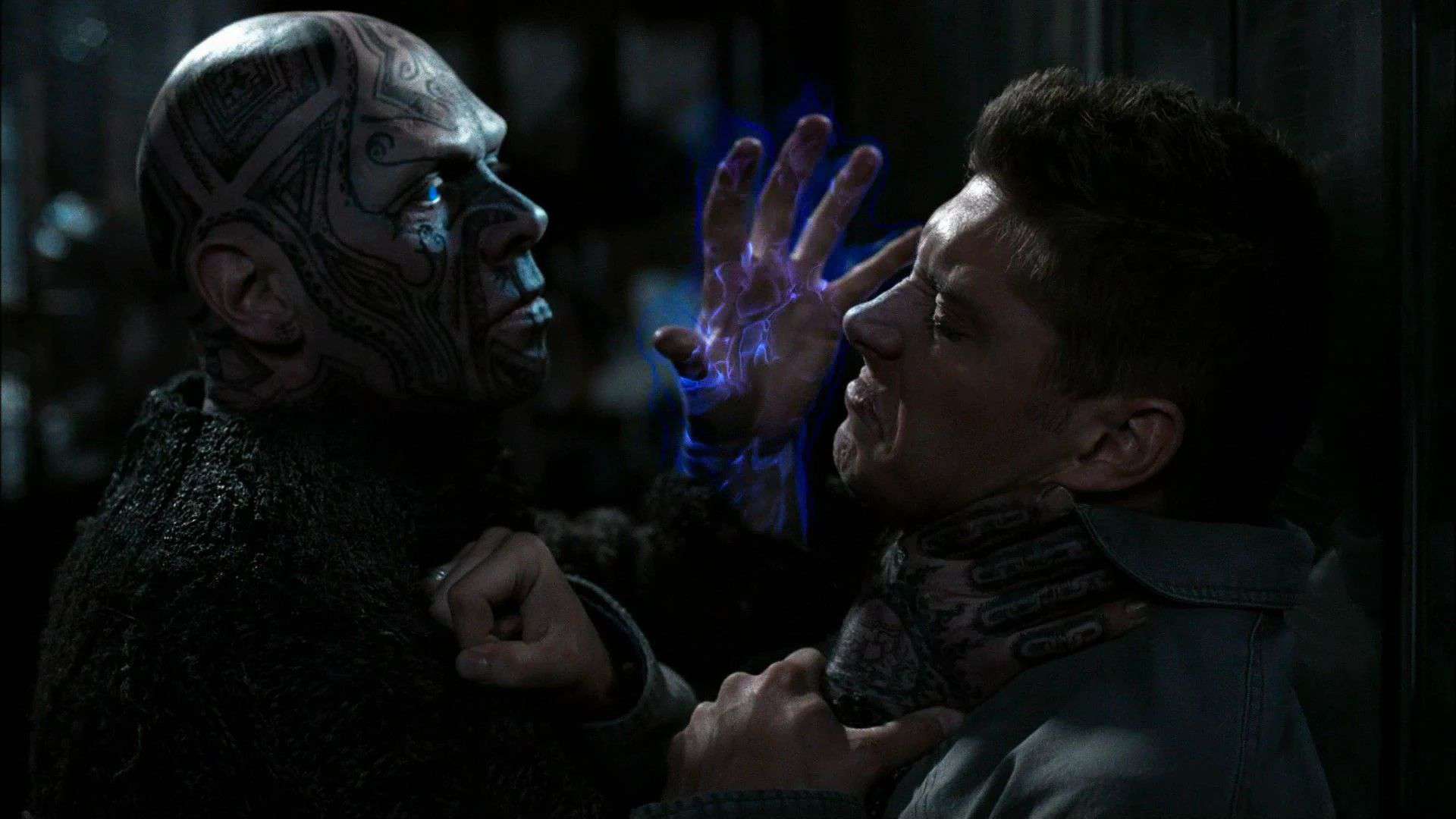 Mackenzie Gray holds a glowing blue hand to Jensen Ackles' face in this image from Warner Bros. Television.