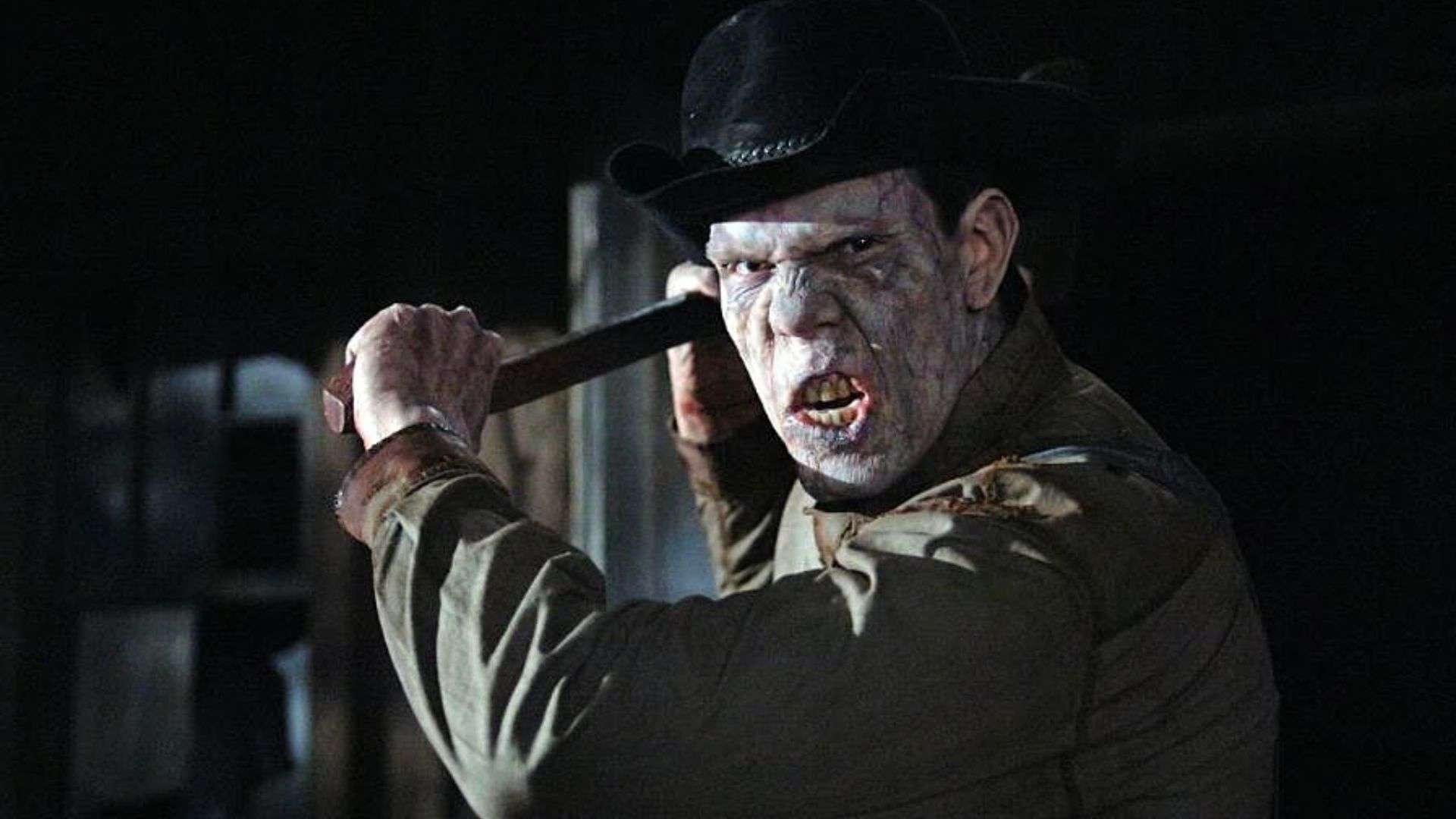 A man in a black hat wielding a hatchet in this image from Warner Bros. Television