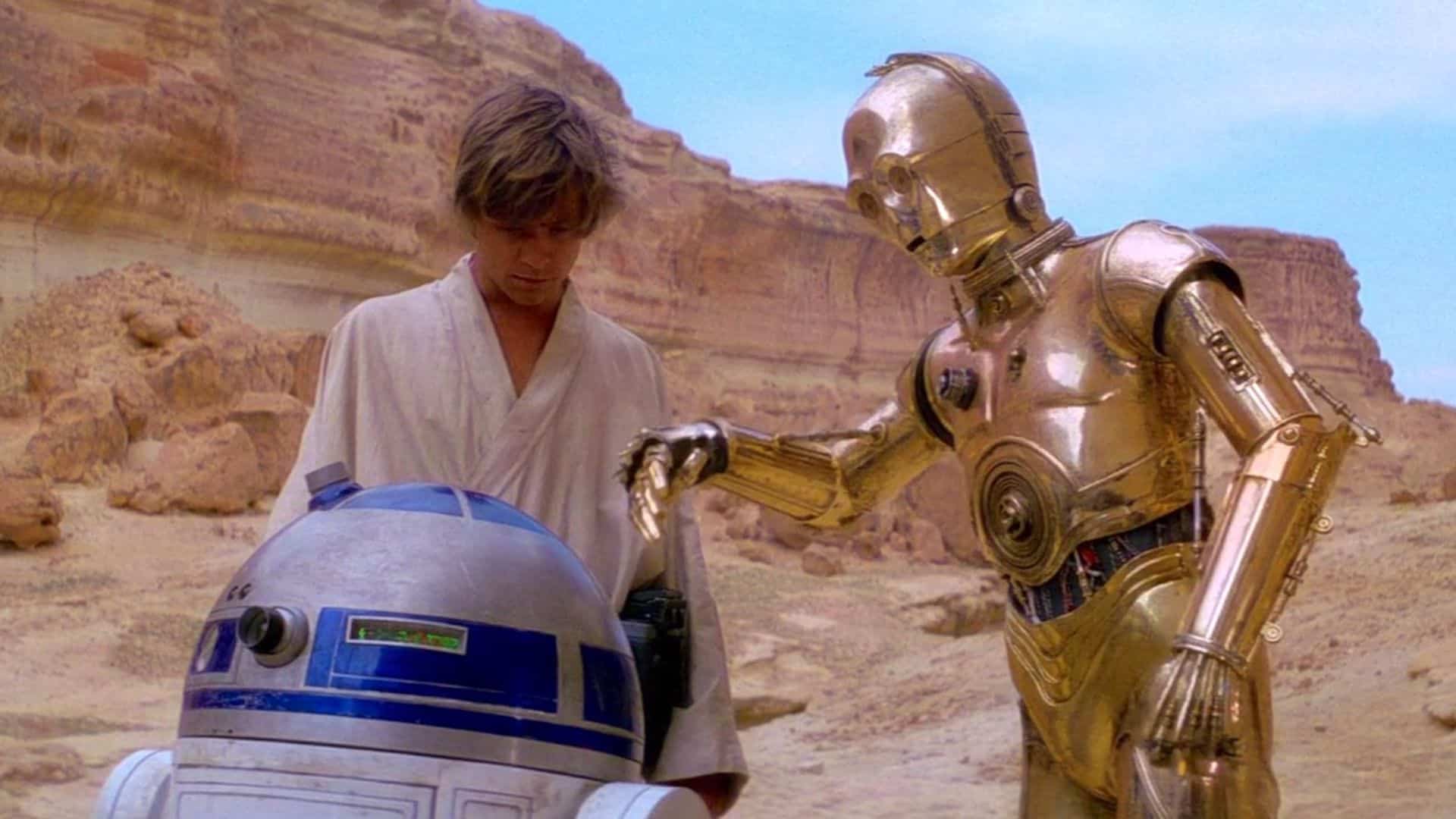 R2-D2, Luke Skywalker, and C-3PO stand in the desert in this image from Lucasfilm.
