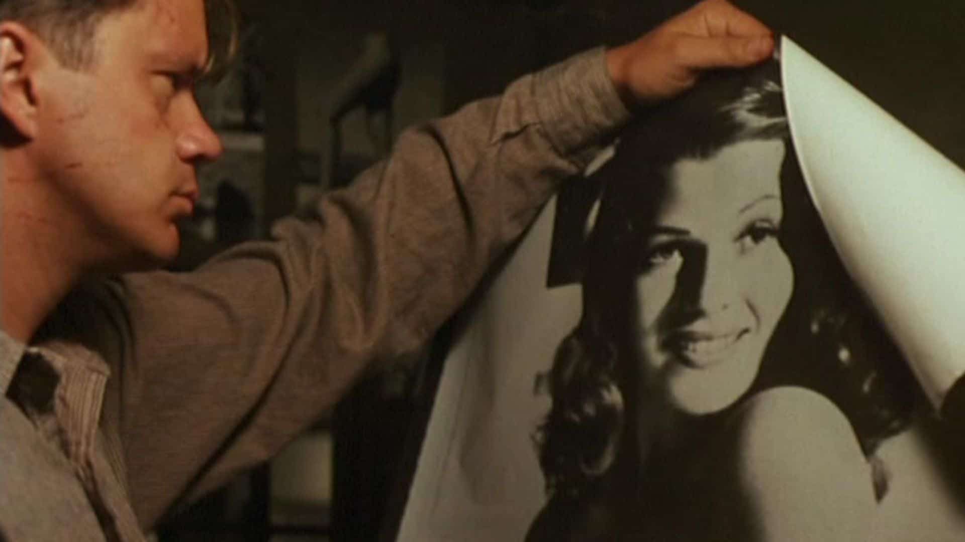 A man looks at a Rita Hayworth poster in this image from Castle Rock Entertainment.