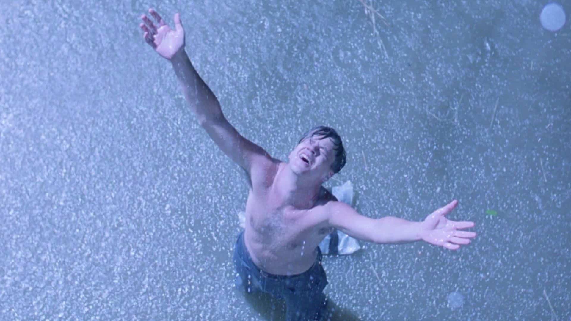  A man, shirtless, stands with arms open in the rain in this image from Castle Rock Entertainment.