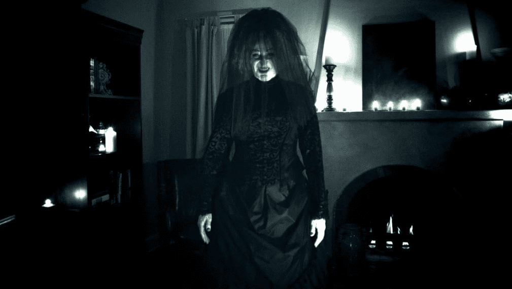 A woman dressed in black stands creepily in the living room in this image from Haunted Movies.