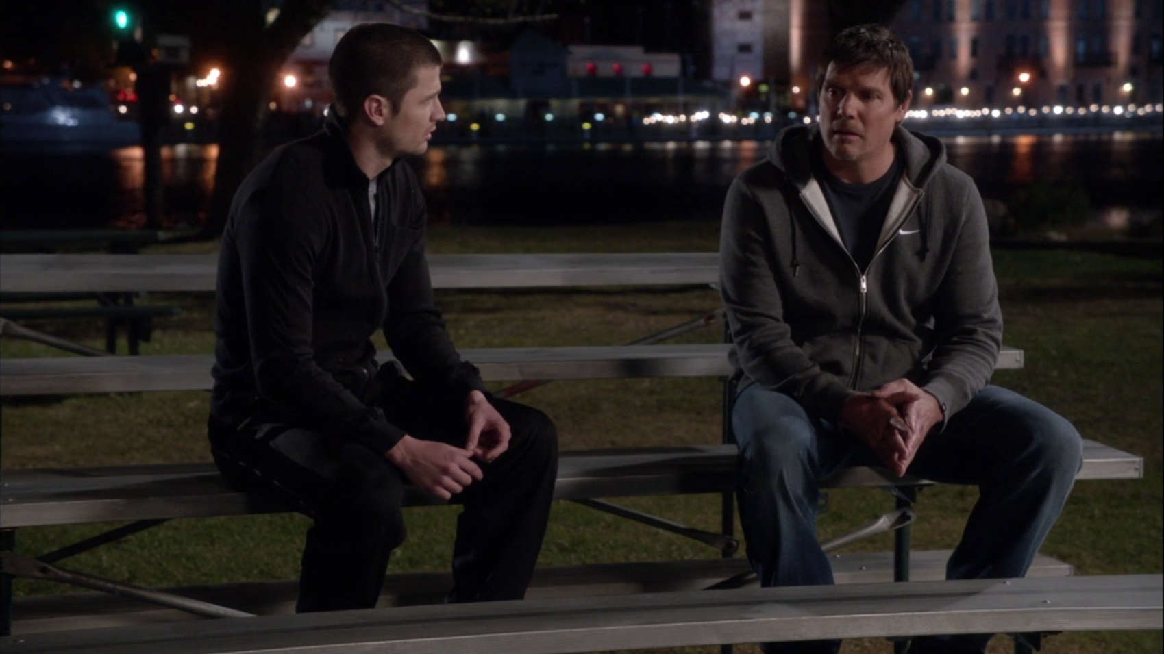 A father and son sit on bleachers next to a basketball court in this image from Tollin/Robbins Productions.