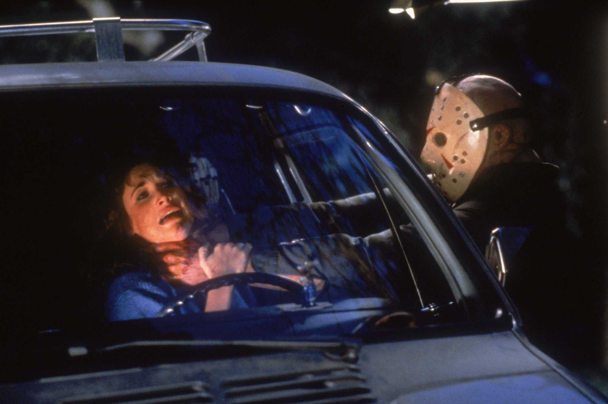 A hockey-masked man strangling a woman through a car window in this photo from Jason Inc. 
