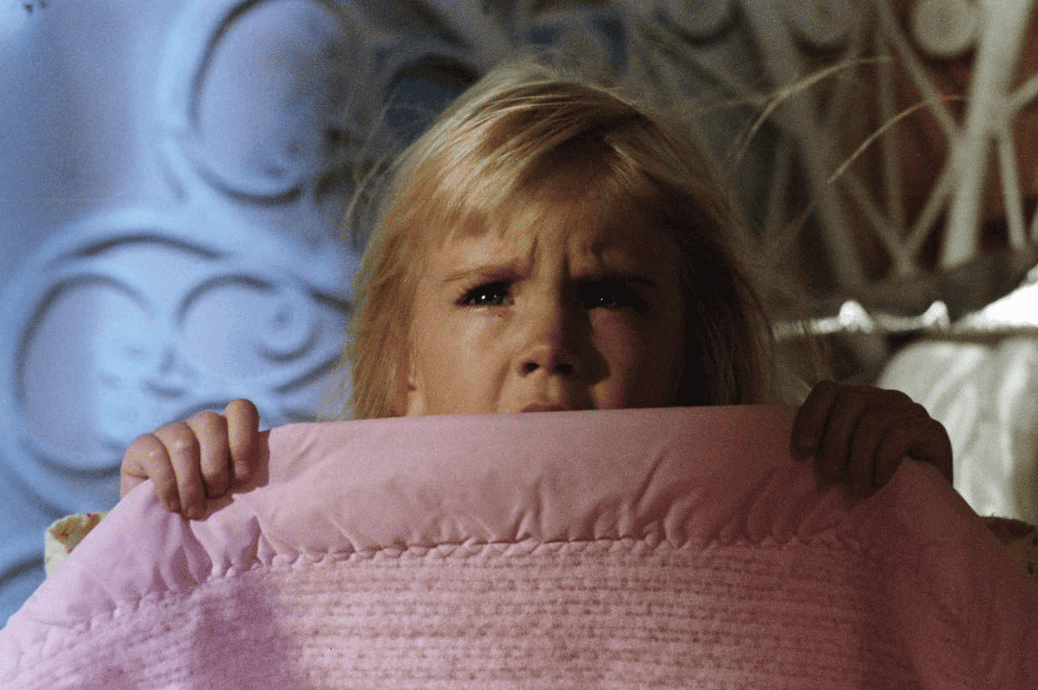 A little girl holds up a blanket in this image from Metro-Goldwyn-Mayer.