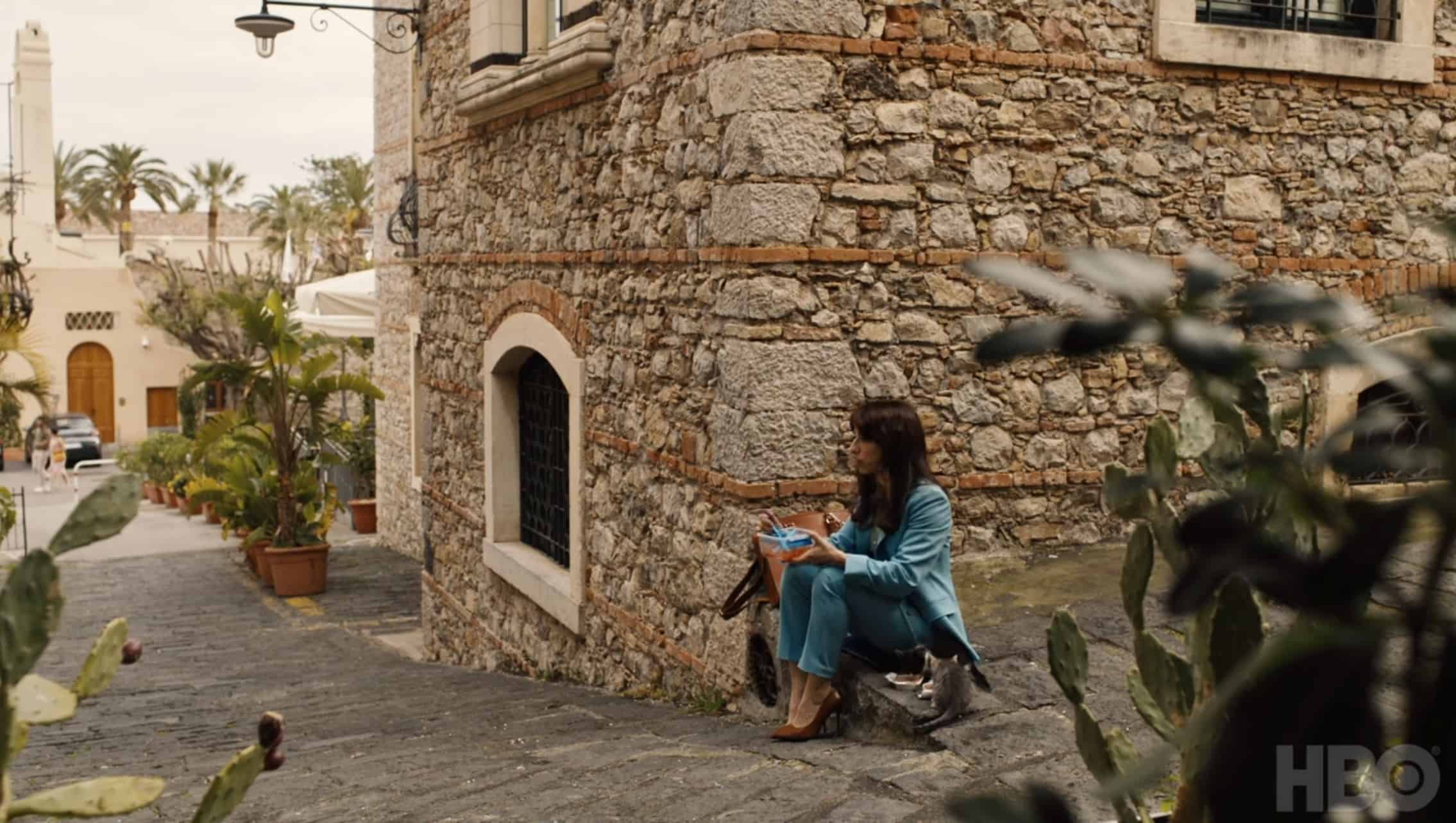 A woman sits on the sidewalk in Sicily in this photo from Rip Cord Productions.