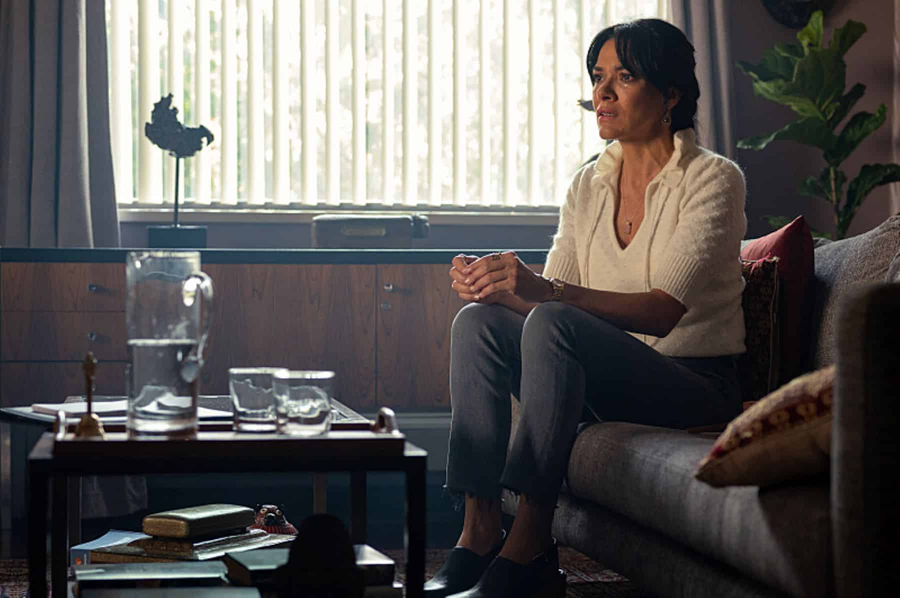 A woman sitting on a couch looks at something out of frame in this photo by Showtime.