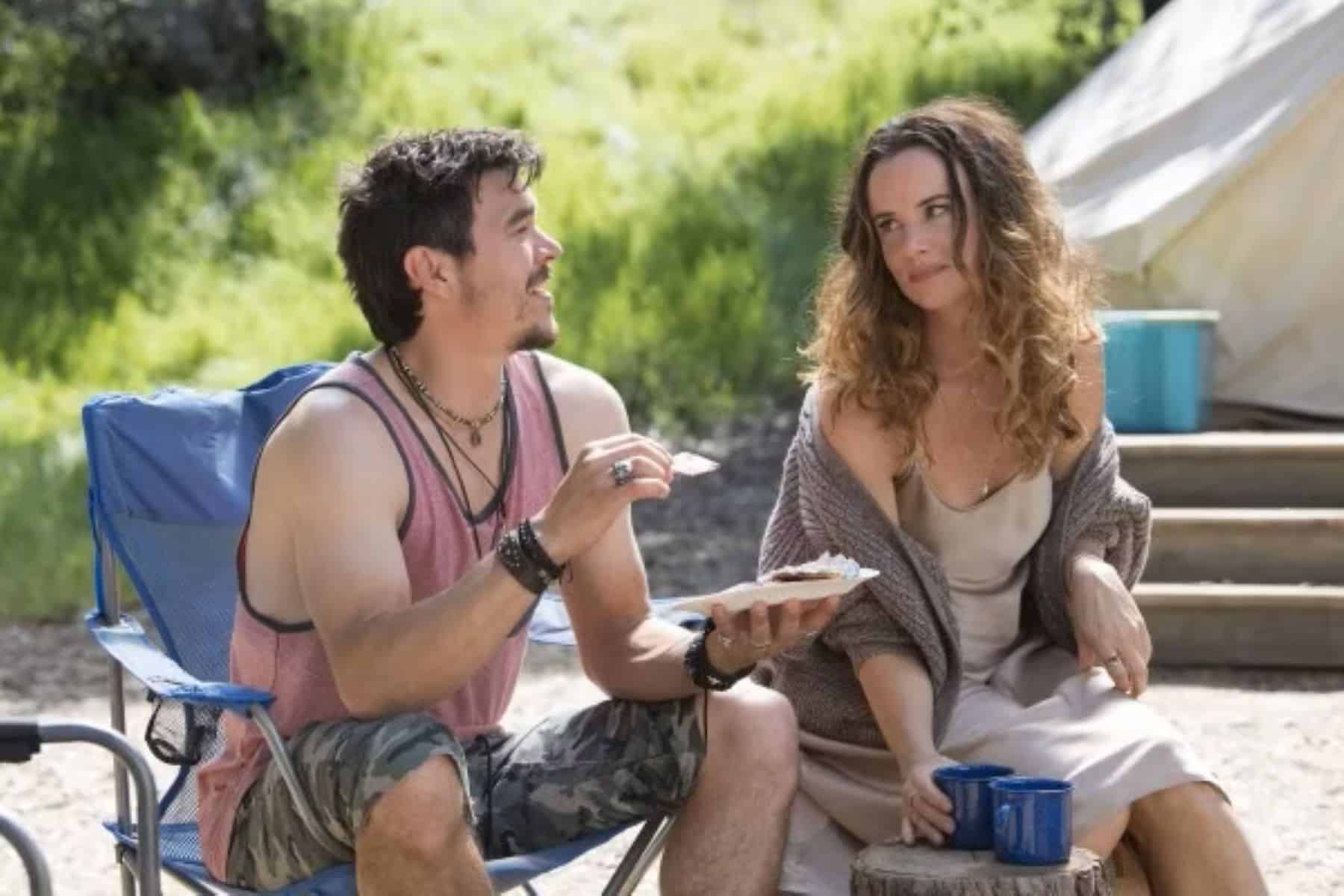 A man and a woman sit at a campsite and have a discussion in this image from Baby Cow Productions.