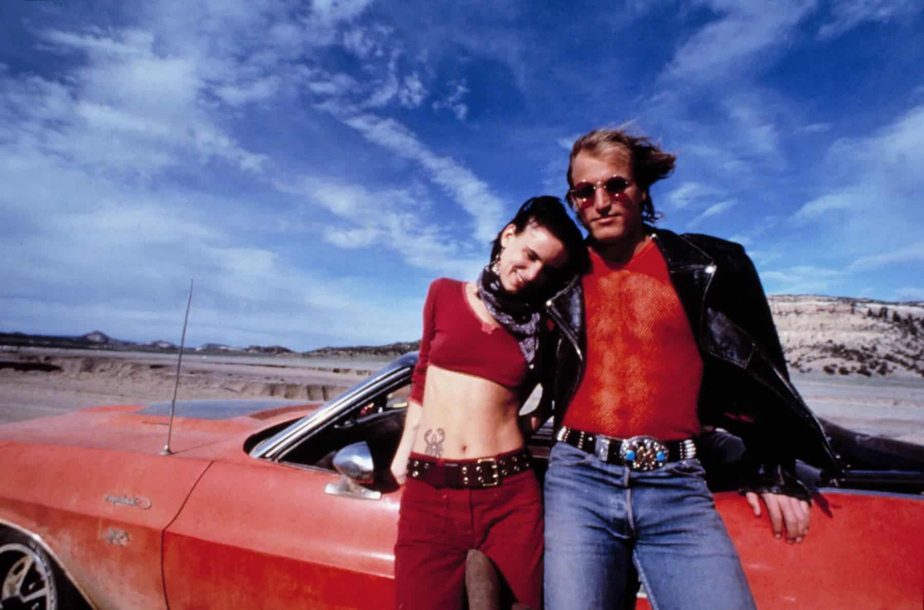 A man and a woman stand in front of a car in this image from Regency Enterprises.