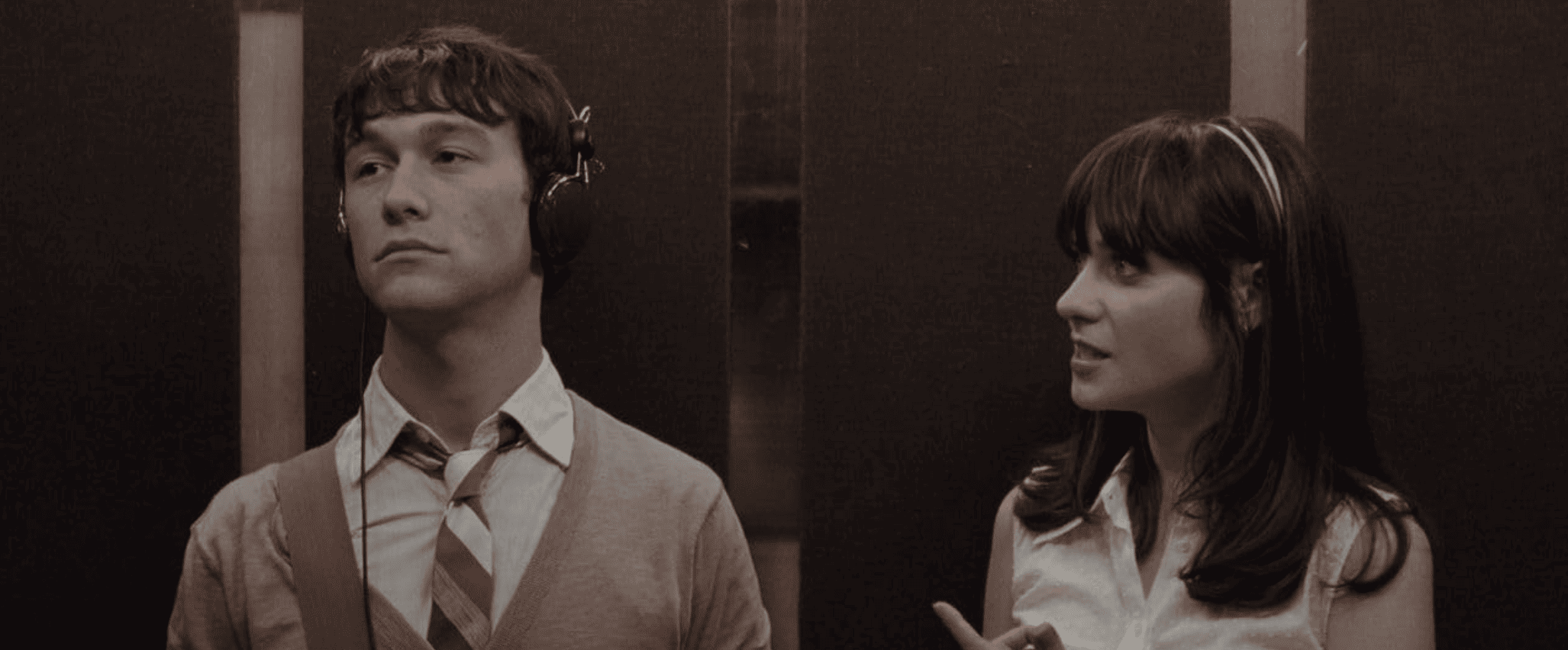 A man listens to headphones as a woman tries to talk to him in an elevator in this image from Searchlight Pictures.