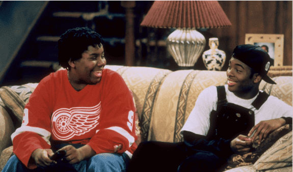 Two boys sitting together on a couch and laughing while staring at each other in this image from Nickelodeon Network.